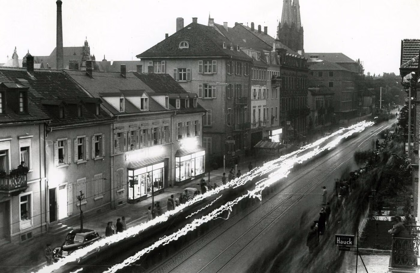 Historische Nachtaufnahme einer Freiburger Straße mit beleuchtetem Ladengeschäft, Langzeitbelichtung