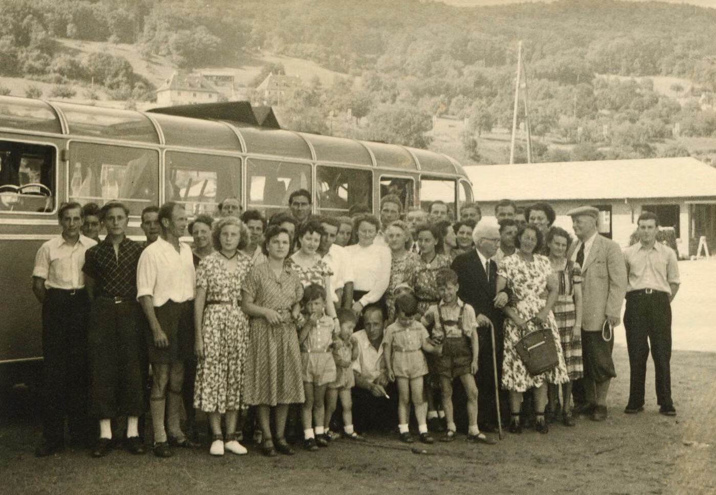 Schwarz-weiß-Gruppenfoto der Belegschaft vor einem Reisebus beim Betriebsausflug