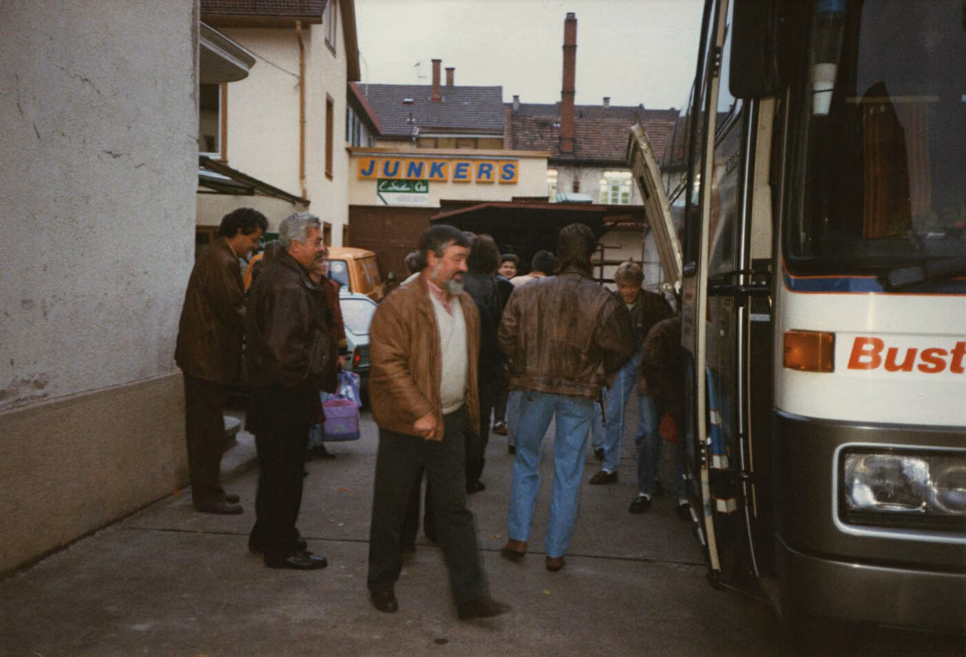 Belegschaft steigt vor dem Firmengebäude mit Junkers-Werbeschild in einen Reisebus